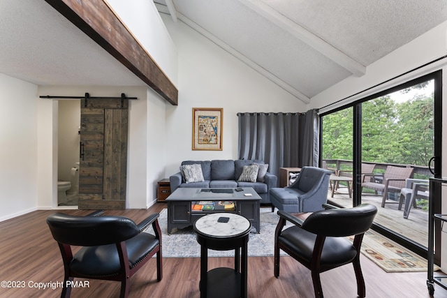 living room featuring a barn door, baseboards, wood finished floors, a textured ceiling, and beam ceiling