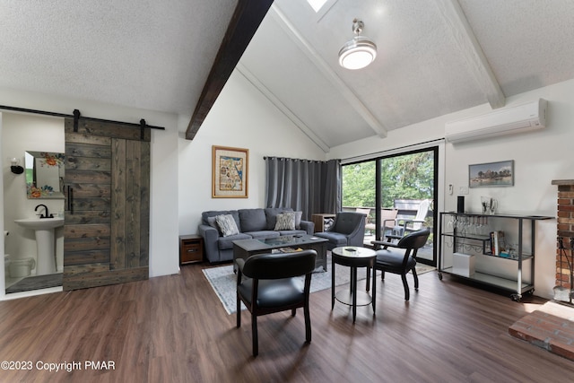 living area with a textured ceiling, a barn door, wood finished floors, a wall mounted AC, and beamed ceiling