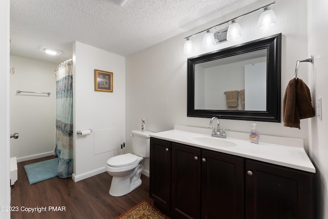 bathroom with a textured ceiling, toilet, wood finished floors, vanity, and baseboards