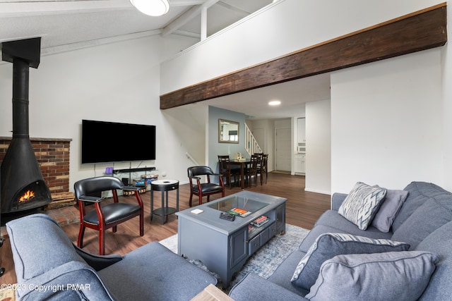 living room with a wood stove, vaulted ceiling with beams, stairway, and wood finished floors