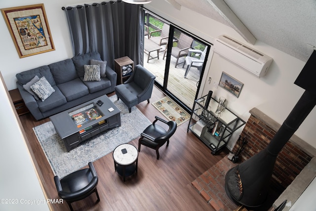 living room featuring a textured ceiling, beam ceiling, wood finished floors, and an AC wall unit