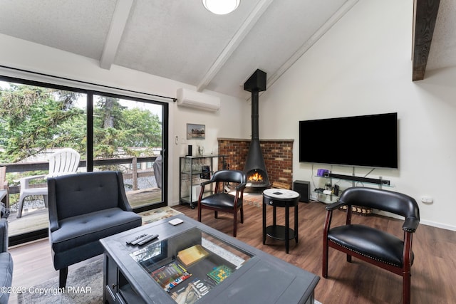 living area with lofted ceiling with beams, wood finished floors, a wood stove, a textured ceiling, and an AC wall unit