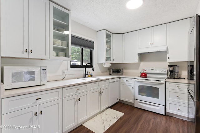 kitchen featuring white appliances, white cabinetry, a sink, and under cabinet range hood