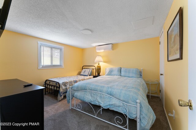 carpeted bedroom with a textured ceiling, a wall unit AC, and baseboards