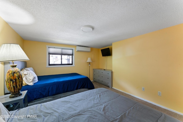 bedroom featuring a textured ceiling, carpet floors, a wall mounted AC, and baseboards