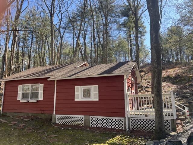 view of property exterior featuring a deck and a shingled roof