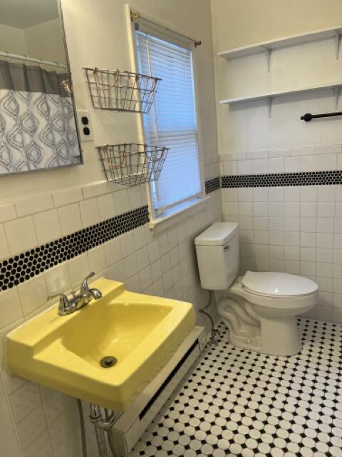 full bath featuring a healthy amount of sunlight, a sink, tile patterned flooring, curtained shower, and toilet