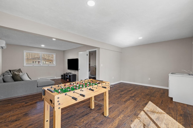 playroom featuring a sink, a wall mounted air conditioner, baseboards, and wood finished floors