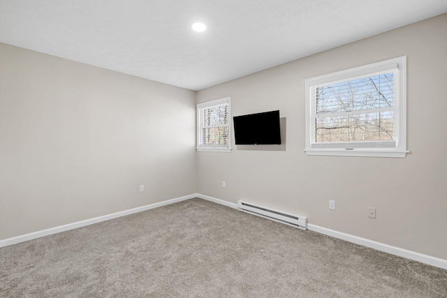 carpeted spare room with a baseboard radiator and baseboards