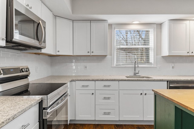 kitchen featuring a sink, white cabinets, appliances with stainless steel finishes, backsplash, and butcher block counters