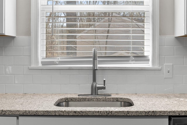 kitchen with a sink, decorative backsplash, a wealth of natural light, and white cabinets