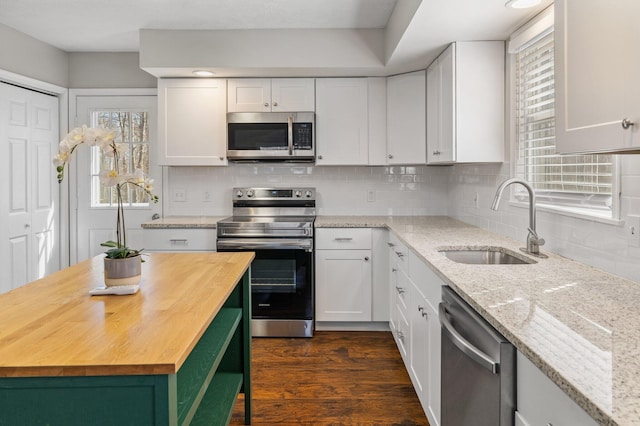 kitchen with dark wood-type flooring, stainless steel appliances, white cabinetry, wood counters, and a sink