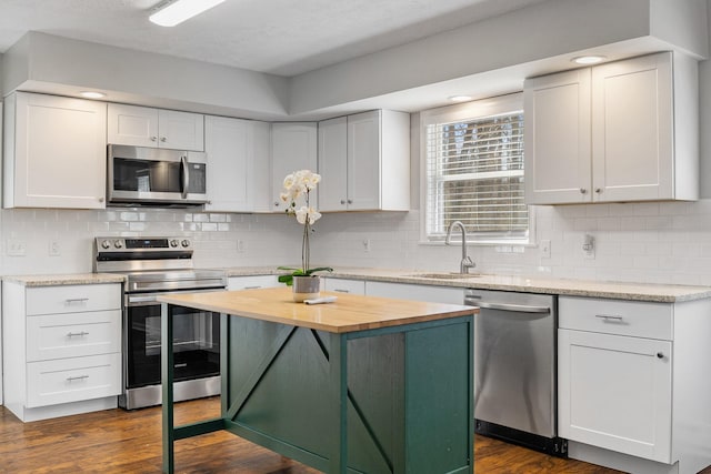 kitchen featuring dark wood-style floors, white cabinets, appliances with stainless steel finishes, and wood counters