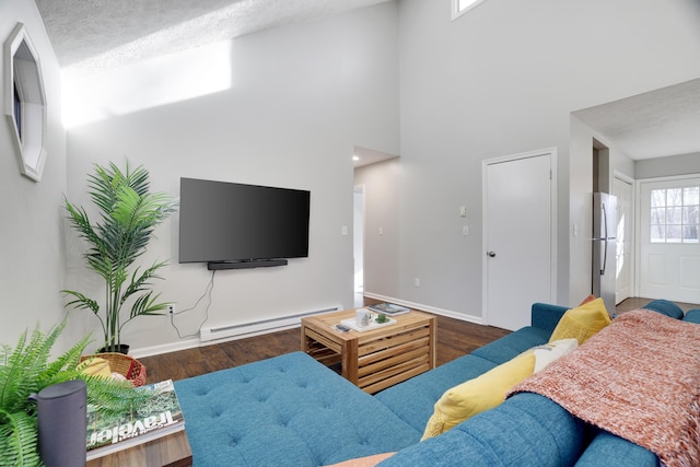 living area featuring a baseboard radiator, baseboards, a high ceiling, and wood finished floors