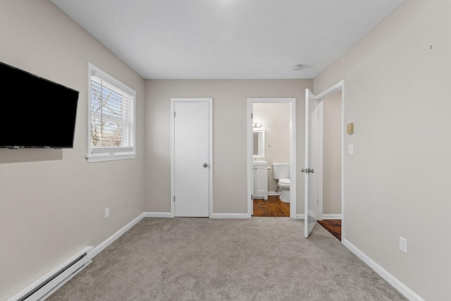 unfurnished bedroom featuring ensuite bathroom, baseboards, carpet floors, and a baseboard radiator