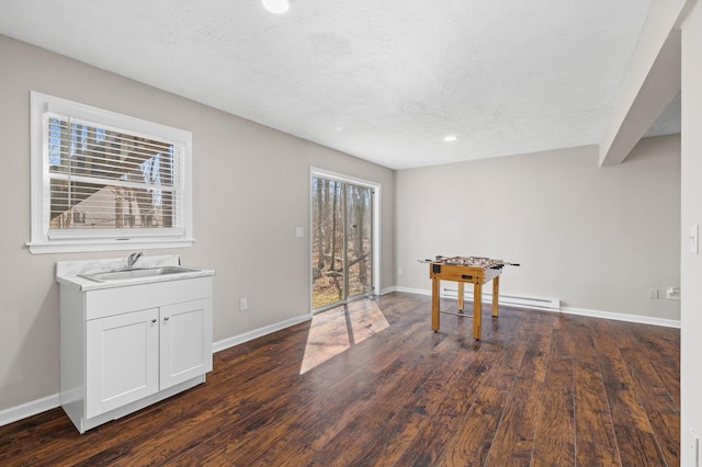 interior space with a sink, baseboards, a textured ceiling, and dark wood finished floors