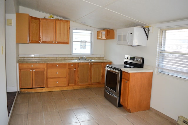 kitchen featuring white microwave, light countertops, lofted ceiling, electric stove, and a sink