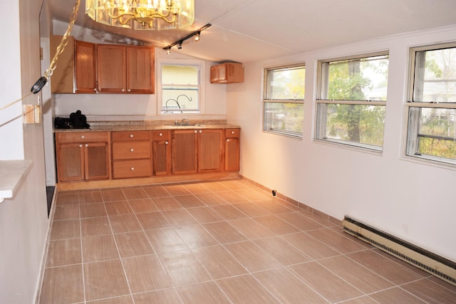 kitchen with a sink, track lighting, a baseboard heating unit, a notable chandelier, and brown cabinets