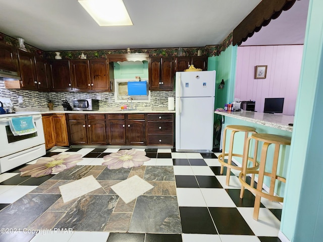 kitchen with under cabinet range hood, white appliances, a sink, light countertops, and light floors