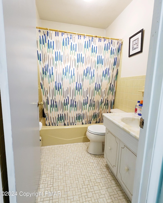 bathroom featuring shower / bath combo with shower curtain, tile walls, toilet, and vanity