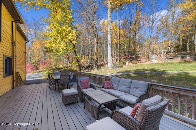 wooden terrace with outdoor dining area, an outdoor hangout area, and a view of trees