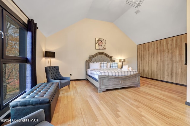 bedroom with baseboards, visible vents, vaulted ceiling, and wood finished floors