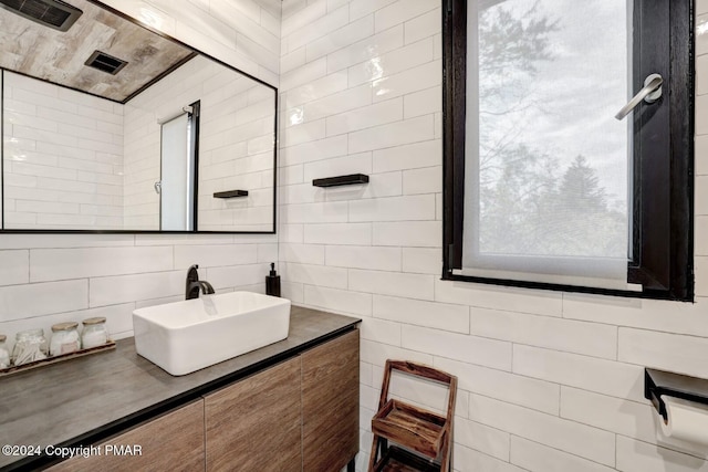 bathroom with visible vents, backsplash, tile walls, and vanity