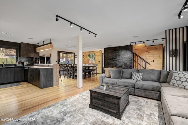 living room featuring stairway, rail lighting, visible vents, and light wood finished floors