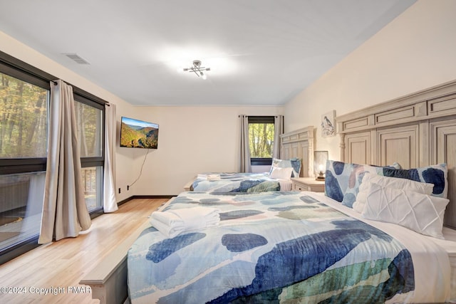 bedroom with light wood-style floors, visible vents, and baseboards