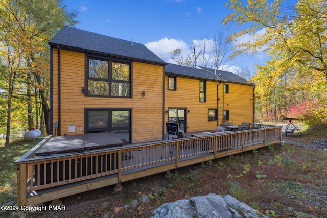 rear view of property with a shingled roof and a deck