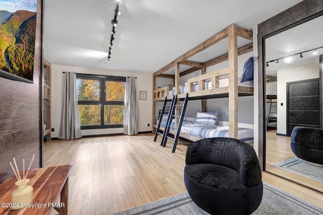 bedroom with track lighting and wood finished floors