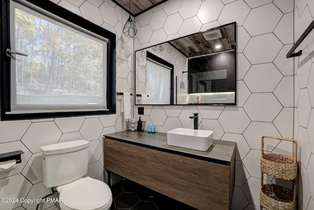 bathroom featuring toilet, tile walls, and vanity