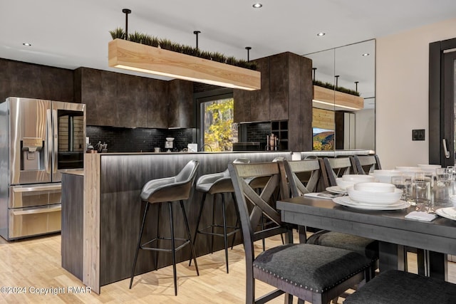 kitchen featuring tasteful backsplash, dark brown cabinetry, stainless steel refrigerator with ice dispenser, and modern cabinets