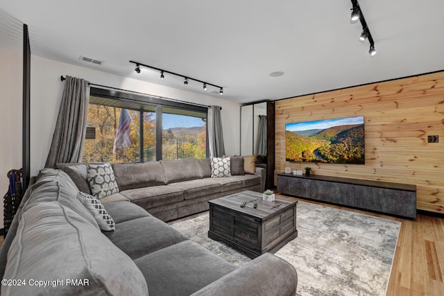 living room featuring wood walls, wood finished floors, visible vents, and track lighting