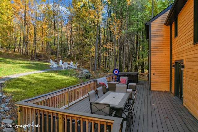 deck featuring a yard, outdoor dining area, and a view of trees