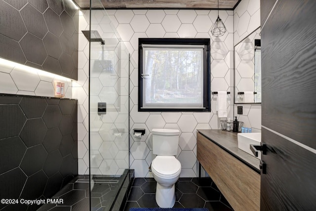 bathroom featuring toilet, tile patterned flooring, a tile shower, and tile walls