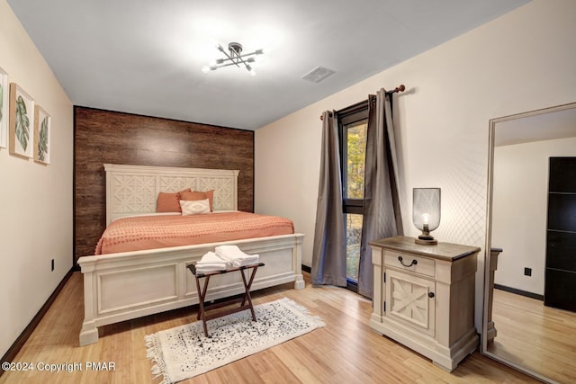 bedroom featuring baseboards, an accent wall, visible vents, and light wood-style floors