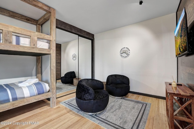 bedroom with a closet, wood finished floors, and baseboards