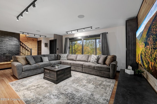 living area featuring visible vents, an accent wall, track lighting, wood finished floors, and stairs