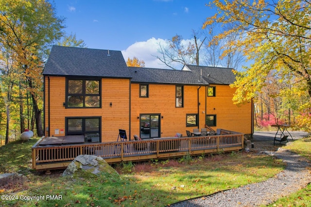 back of property featuring a shingled roof and a deck