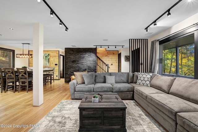 living room featuring light wood-type flooring, rail lighting, and stairs