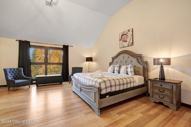 bedroom with lofted ceiling, light wood finished floors, and baseboards