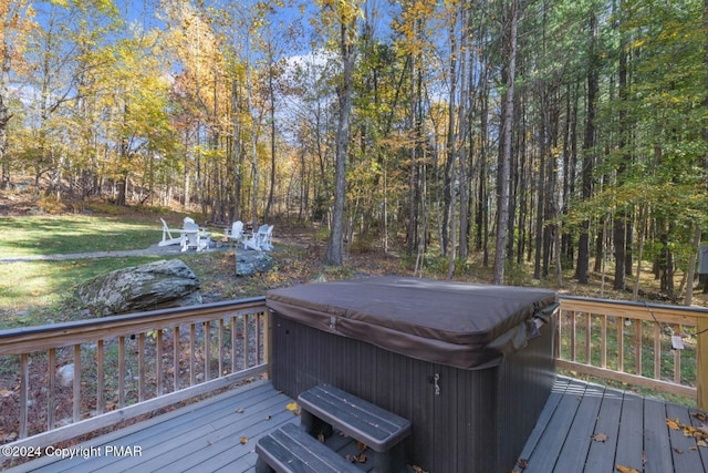 wooden deck featuring a forest view and a hot tub