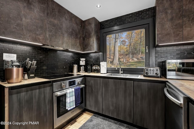 kitchen featuring dark brown cabinetry, stainless steel appliances, light countertops, decorative backsplash, and modern cabinets