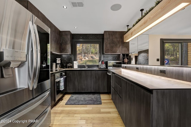 kitchen with stainless steel appliances, visible vents, light wood-style flooring, dark brown cabinets, and modern cabinets