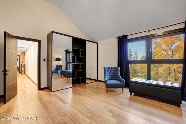 sitting room with light wood finished floors, baseboards, and high vaulted ceiling