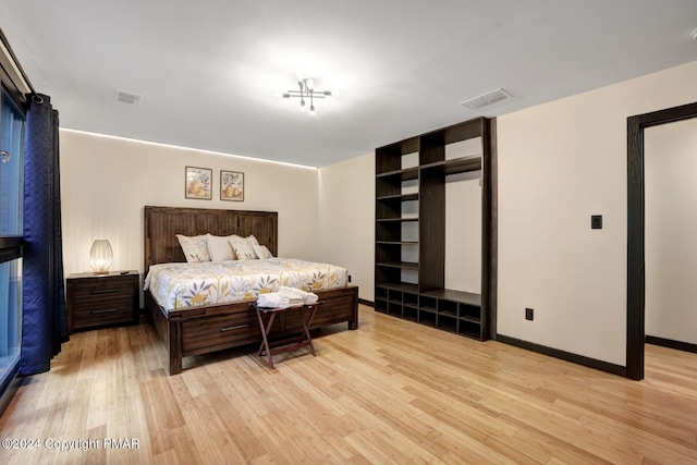 bedroom with light wood finished floors, visible vents, and baseboards