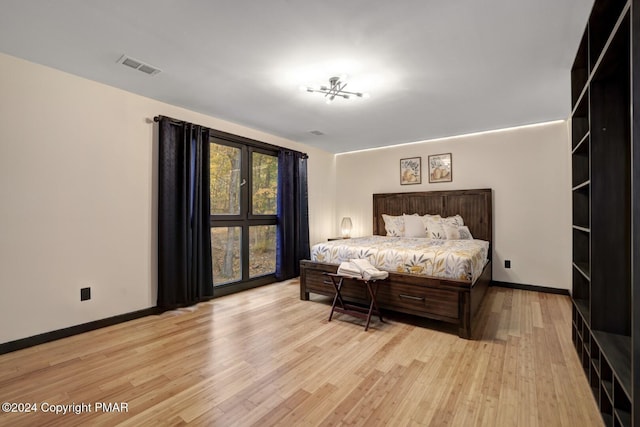 bedroom with light wood-style floors, visible vents, and baseboards