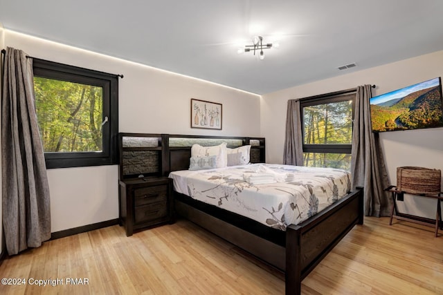 bedroom with baseboards, visible vents, and light wood finished floors