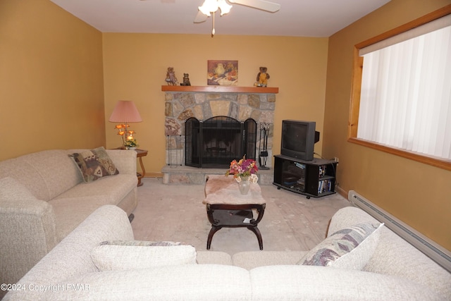 living room with baseboards, a baseboard heating unit, a ceiling fan, and a stone fireplace